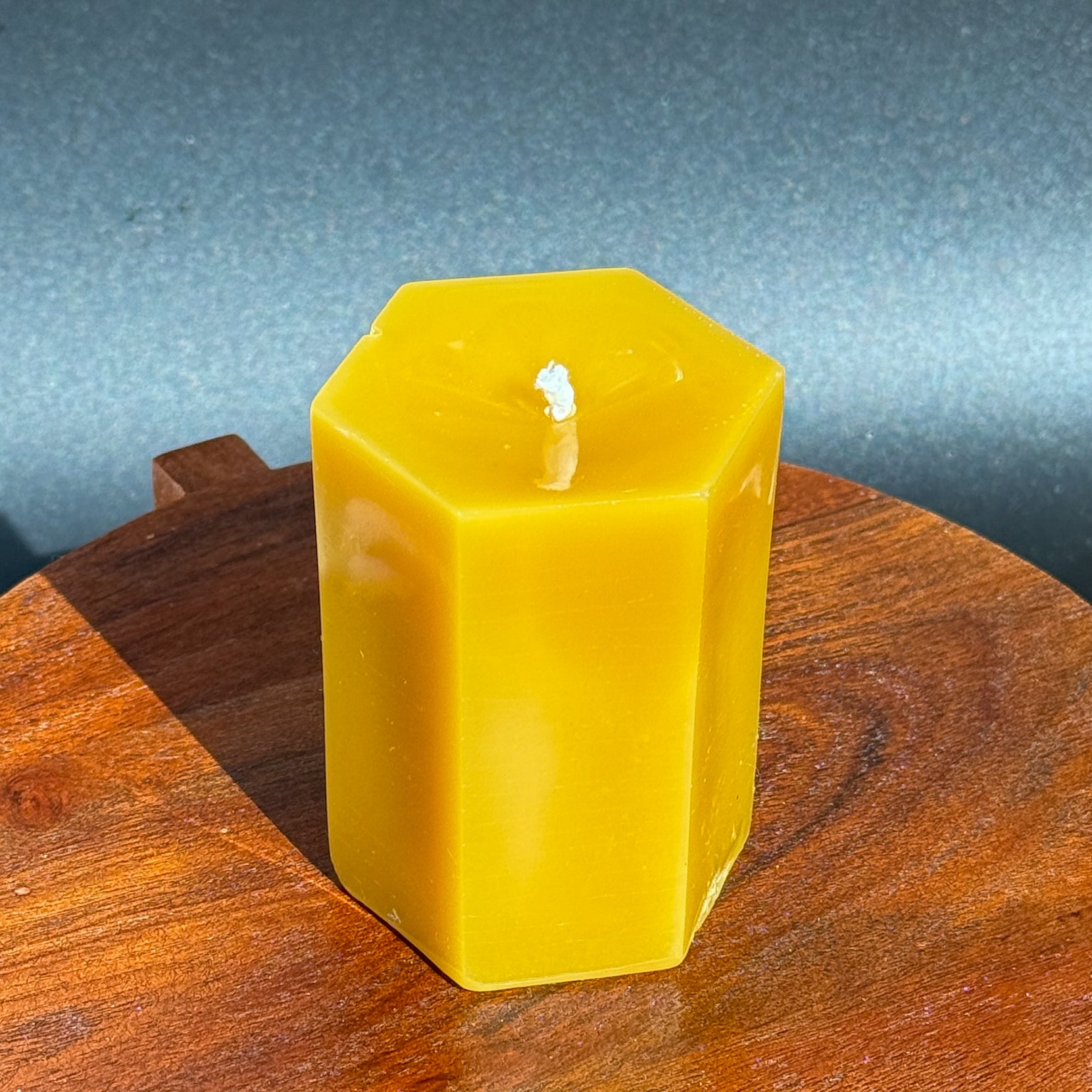 Hexagonal beeswax candle on a wooden surface